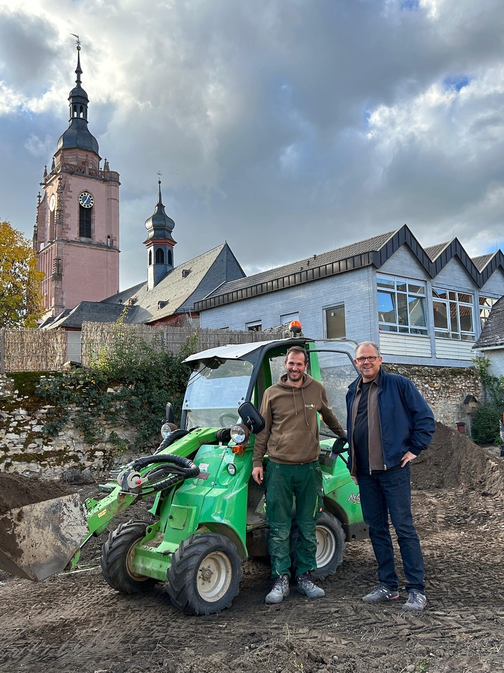 Bürgermeister und Mitarbeiter der Firma stehen neben Bagger