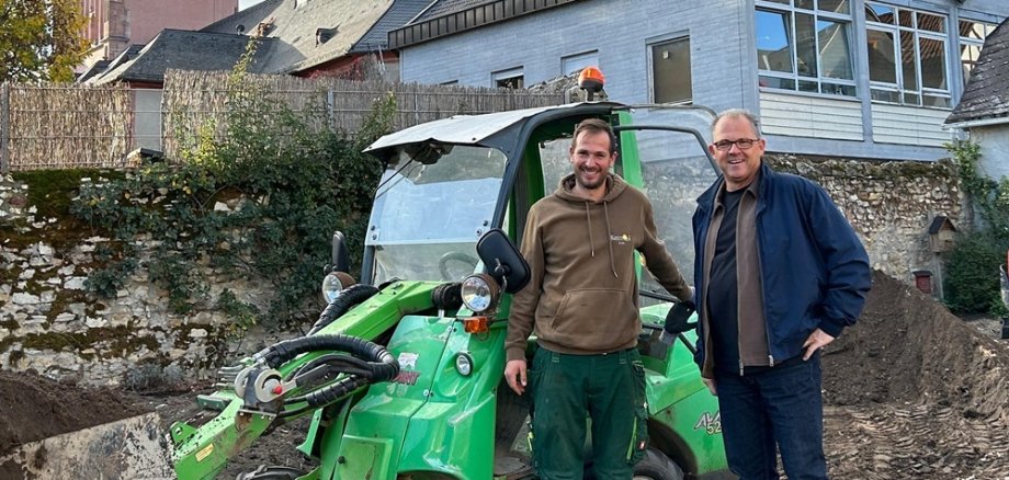 Bürgermeister und Mitarbeiter der Firma stehen neben Bagger